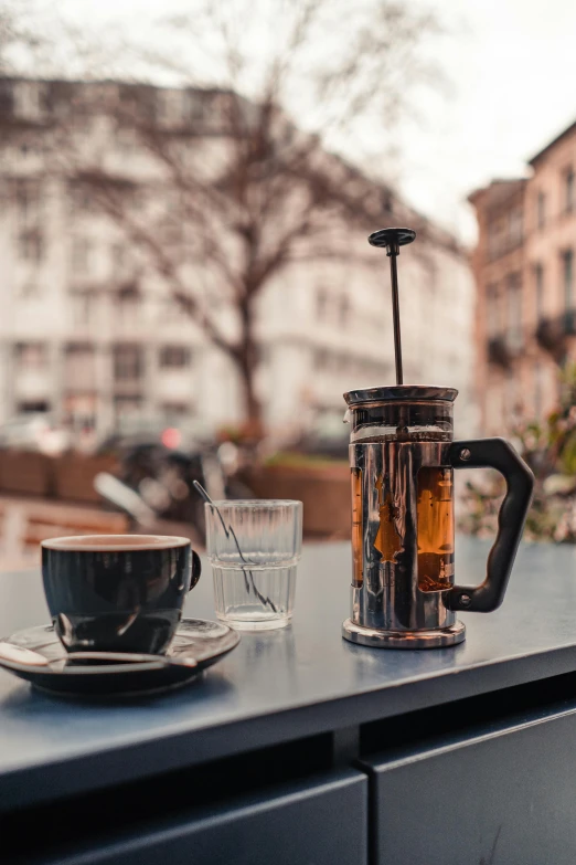 a coffee pot sitting on top of a table next to a cup of coffee, by Niko Henrichon, square, sunny environment, cold brew coffee ), black