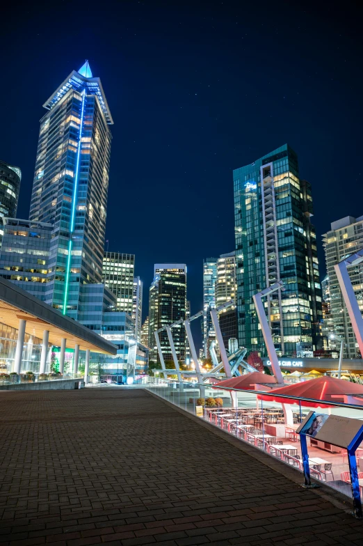 the city skyline is lit up at night, by Chris Rallis, vancouver school, docked at harbor, food court, high resolution photo, 8k resolution”