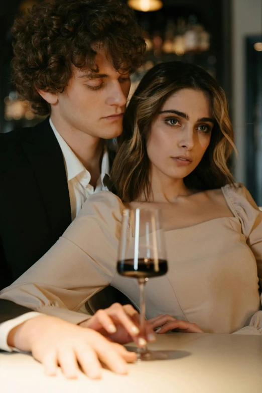 a man and a woman sitting at a table with a glass of wine, a portrait, trending on pexels, looking seductive, sydney hanson, lightly dressed, julia sarda