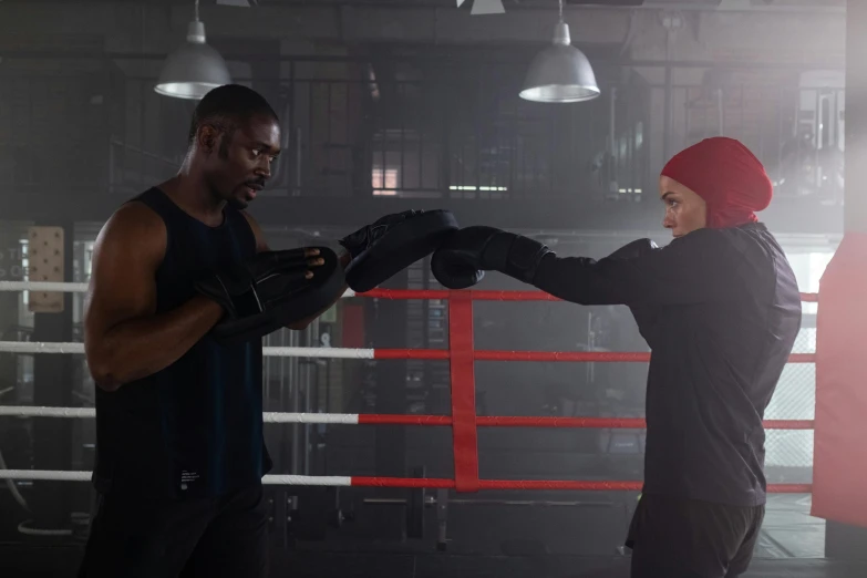 a man standing next to a woman in a boxing ring, by Arabella Rankin, pexels contest winner, he also wears a grey beanie, marvel movie still, kevin hart, working out