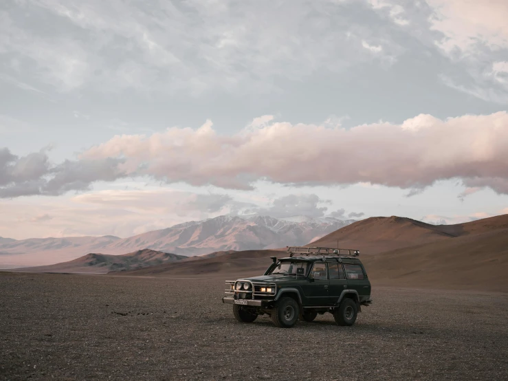 a vehicle that is sitting in the dirt, unsplash contest winner, in a vast serene landscape, muted browns, chile, background image