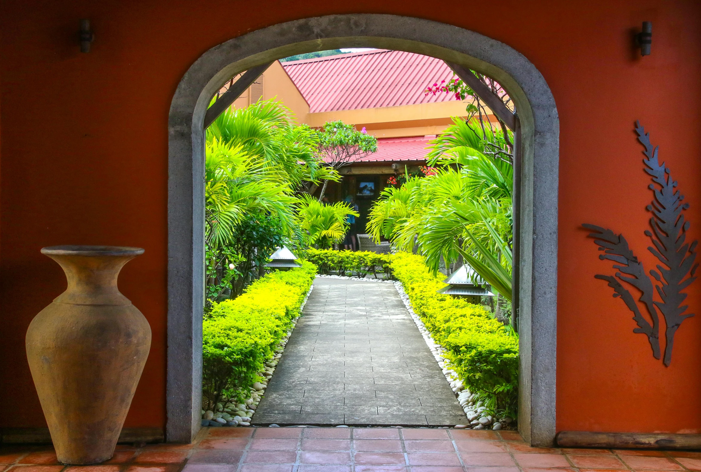 a large vase sitting in the middle of a walkway, archways made of lush greenery, barcelo tomas, exterior photo, paradise garden massage