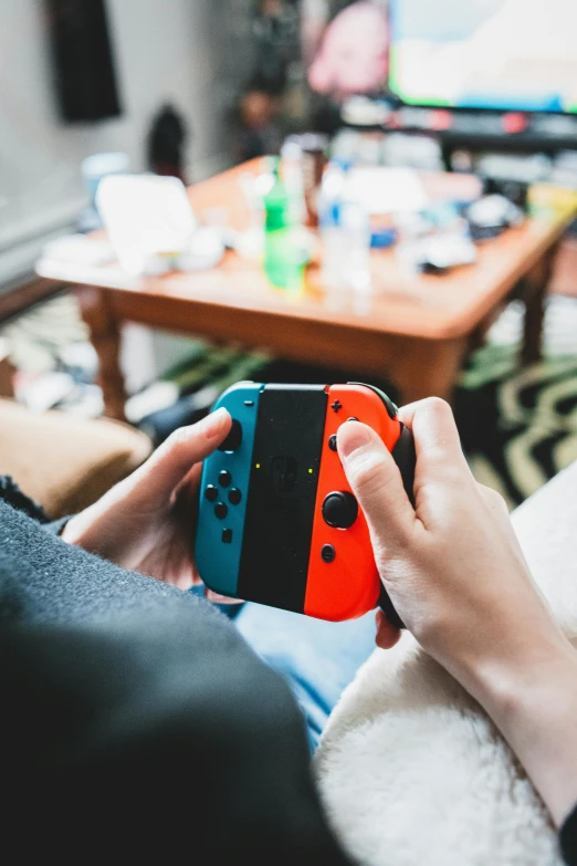 a person sitting on a couch holding a nintendo wii game controller, by Dan Content, unsplash, teenager hangout spot, sitting on a red button, made with unreal engine, a colorful