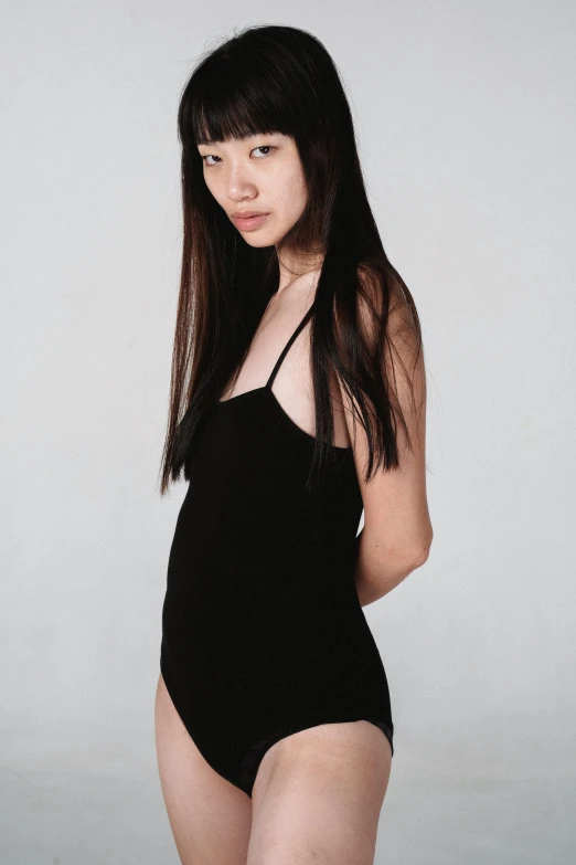 a woman in a black swimsuit posing for a picture, inspired by Wang E, reddit, wearing black camisole outfit, lulu chen, pose 4 of 1 6, plain background