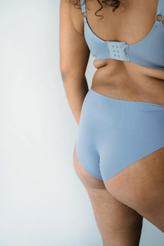 a woman in a blue underwear posing for a picture, oversized_hindquarters, on a gray background, light blue skin, no - text no - logo