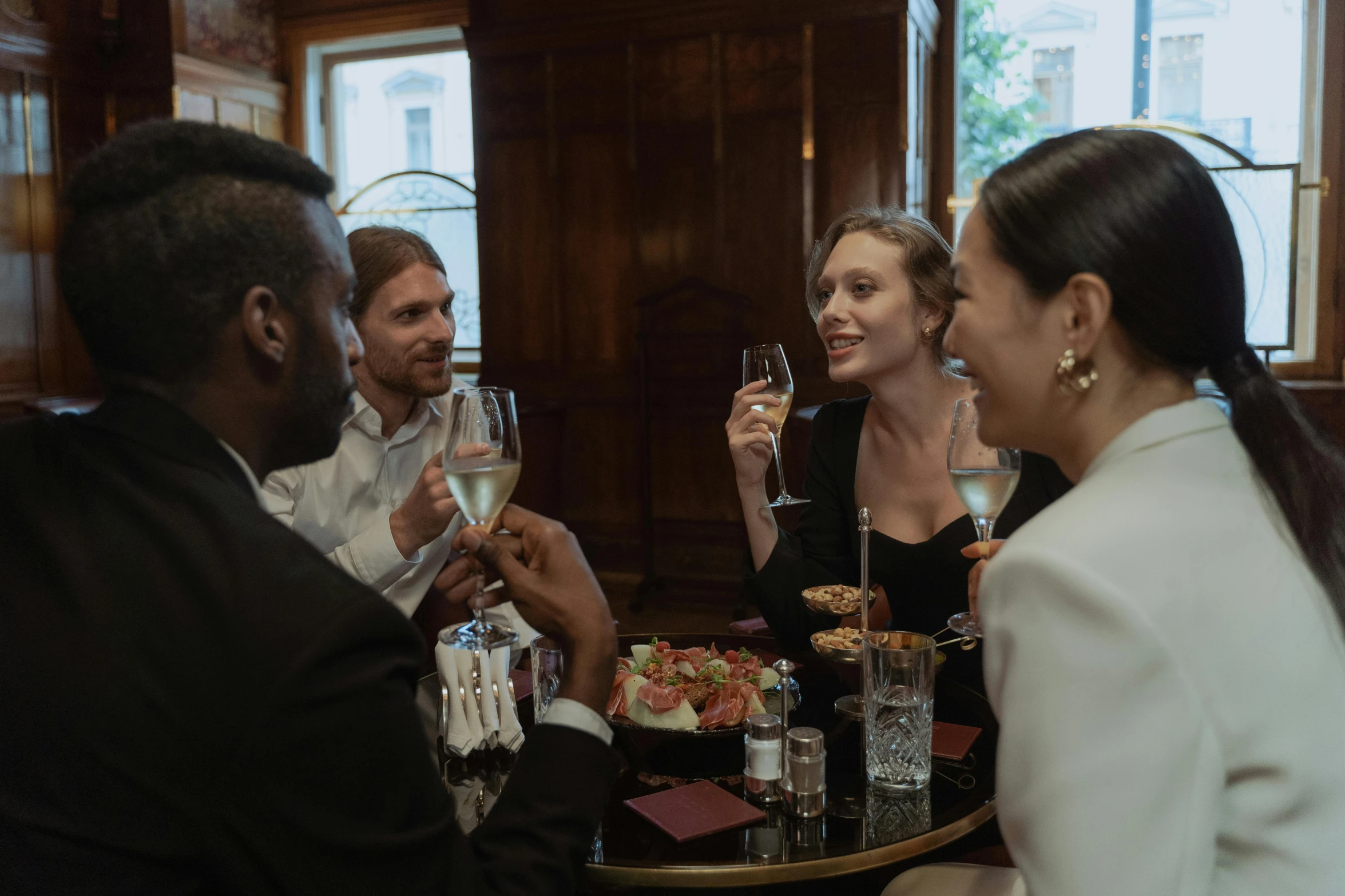 a group of people sitting around a table drinking wine, champagne on the table, multiple stories, thumbnail, item