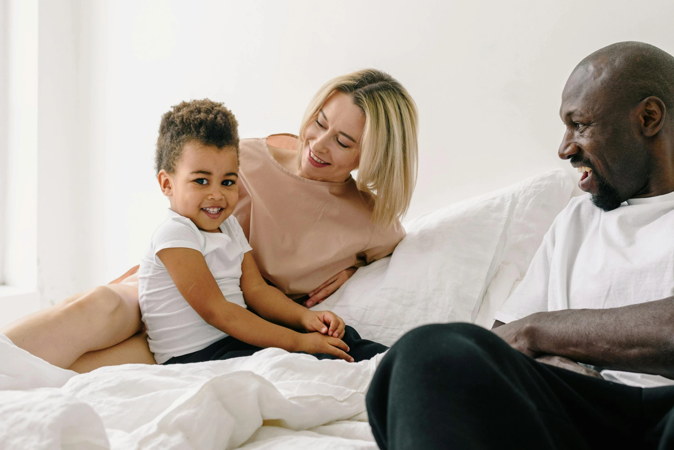 a man sitting on top of a bed next to a woman and a child, pexels contest winner, happening, mixed race, manuka, with a white background, profile image