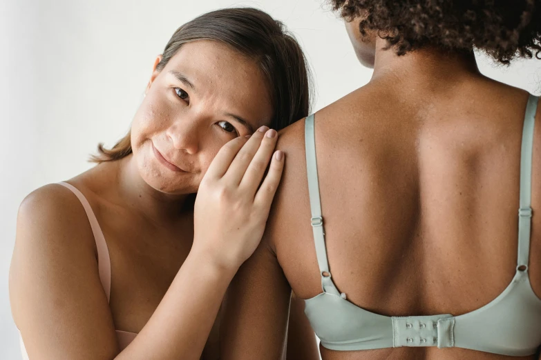 a woman standing next to another woman in a bra, trending on pexels, noticeable tear on the cheek, manuka, embracing, ad image