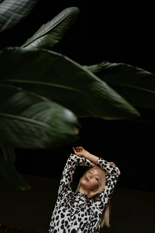 a little girl standing in front of a plant, an album cover, inspired by Elsa Bleda, unsplash, renaissance, arms stretched out, julia garner, in front of a black background, chilling on a leaf