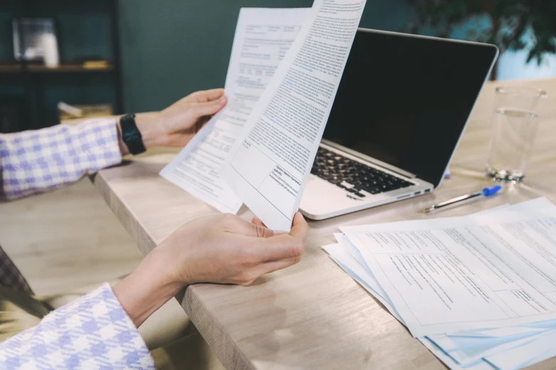 a person sitting at a table with a laptop and papers, pexels contest winner, private press, background image, opening shot, commercial, paper cut out