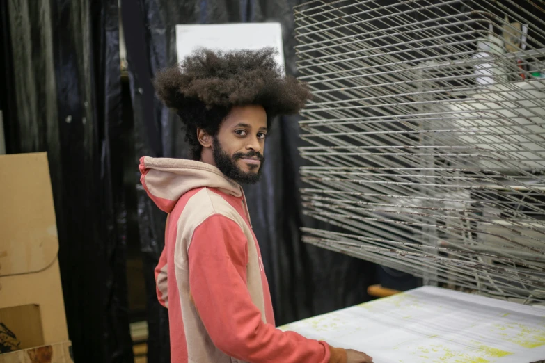 a man that is standing in front of a machine, a silk screen, inspired by Afewerk Tekle, pexels contest winner, long afro hair, weaving, looking happy, ignant
