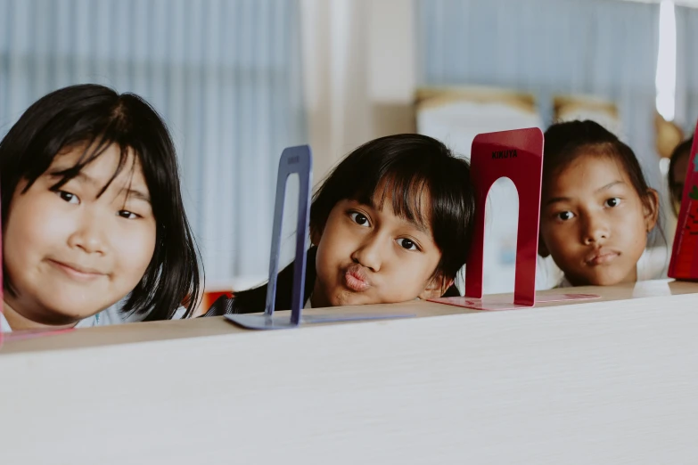 a group of young children sitting next to each other, pexels contest winner, heidelberg school, avatar image, standing on a desk, hiding behind obstacles, profile image