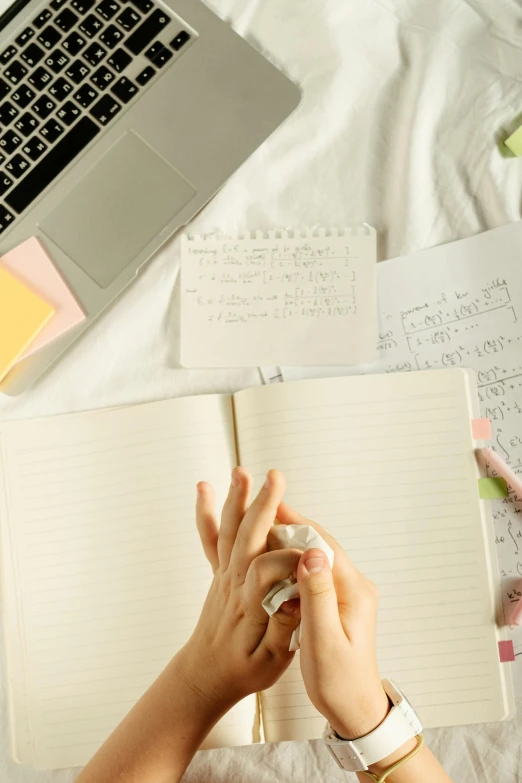 a woman sitting on top of a bed next to a laptop computer, trending on pexels, found scribbled in a notebook, educational supplies, cream paper, hand gesture