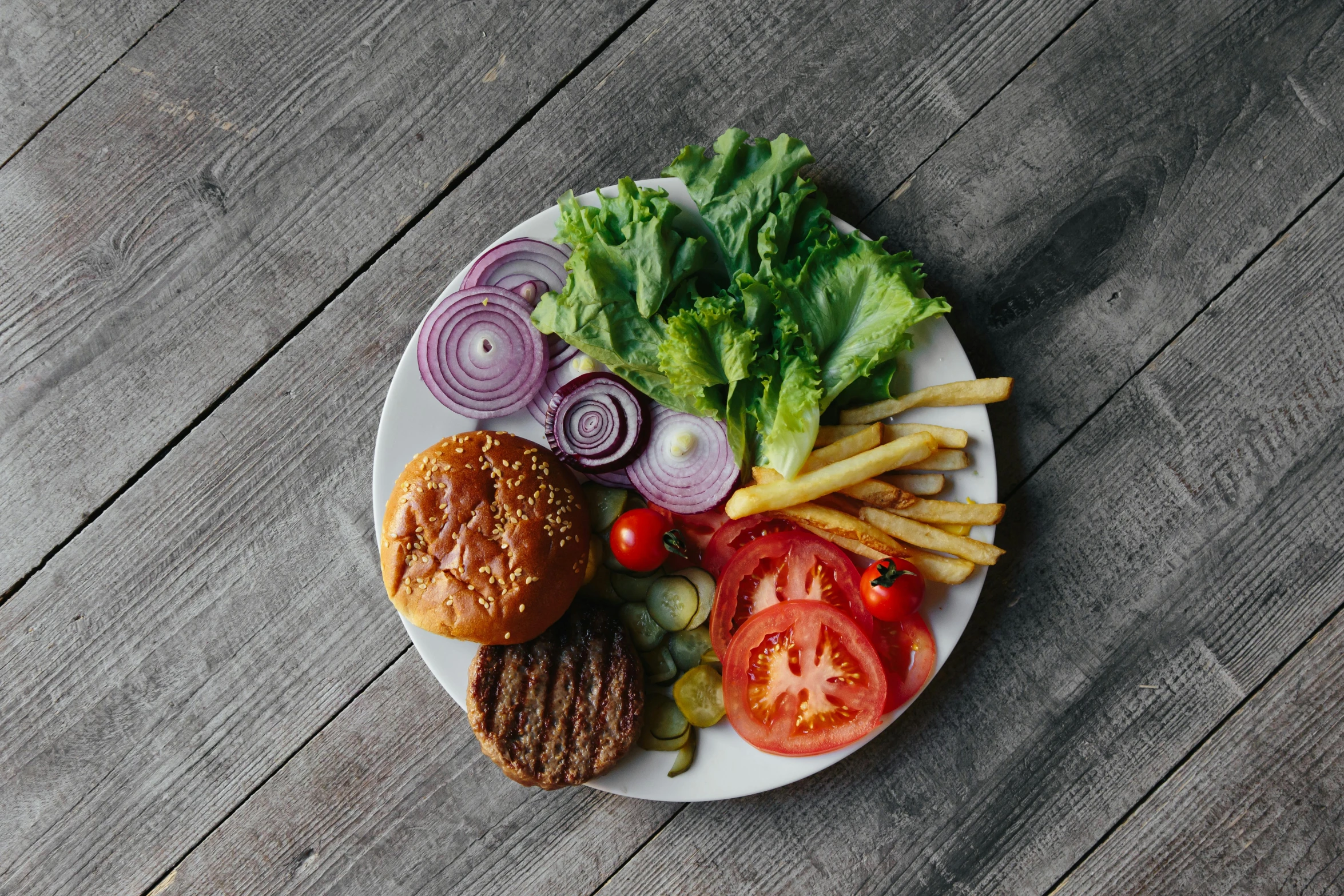 a white plate topped with a burger and french fries, by Carey Morris, unsplash, veggies, extra pickles and onions, greens), 6 pack