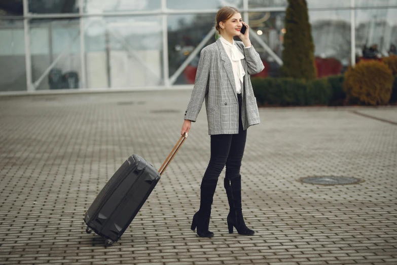 a woman with a suitcase talking on a cell phone, pexels contest winner, happening, grey pants and black dress shoes, olga buzova, hunting, 8ft tall