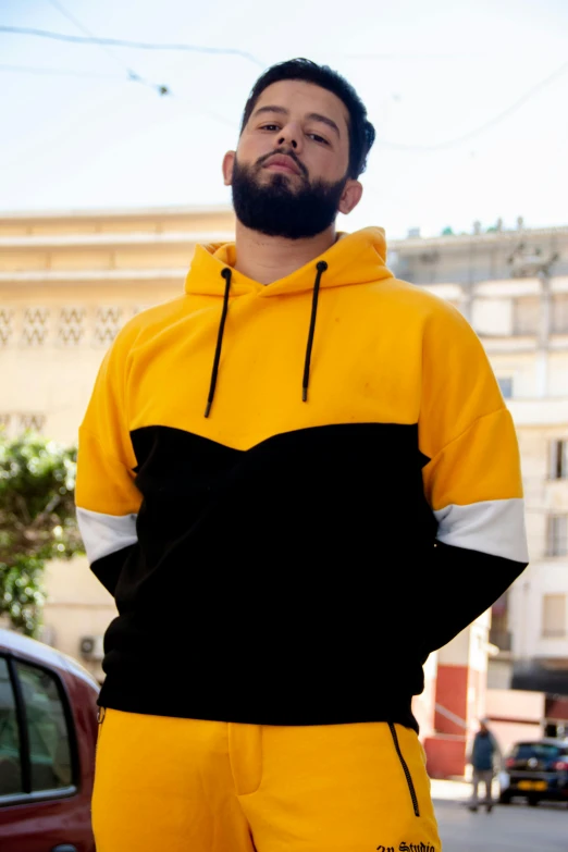 a man with a beard wearing a yellow and black hoodie, mohamed chahin style, colour blocking, egypt, épaule devant pose