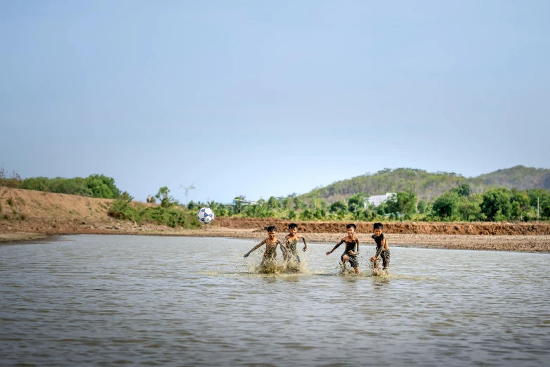 a group of people walking through a body of water, a picture, myanmar, jen atkin, playing, maintenance photo