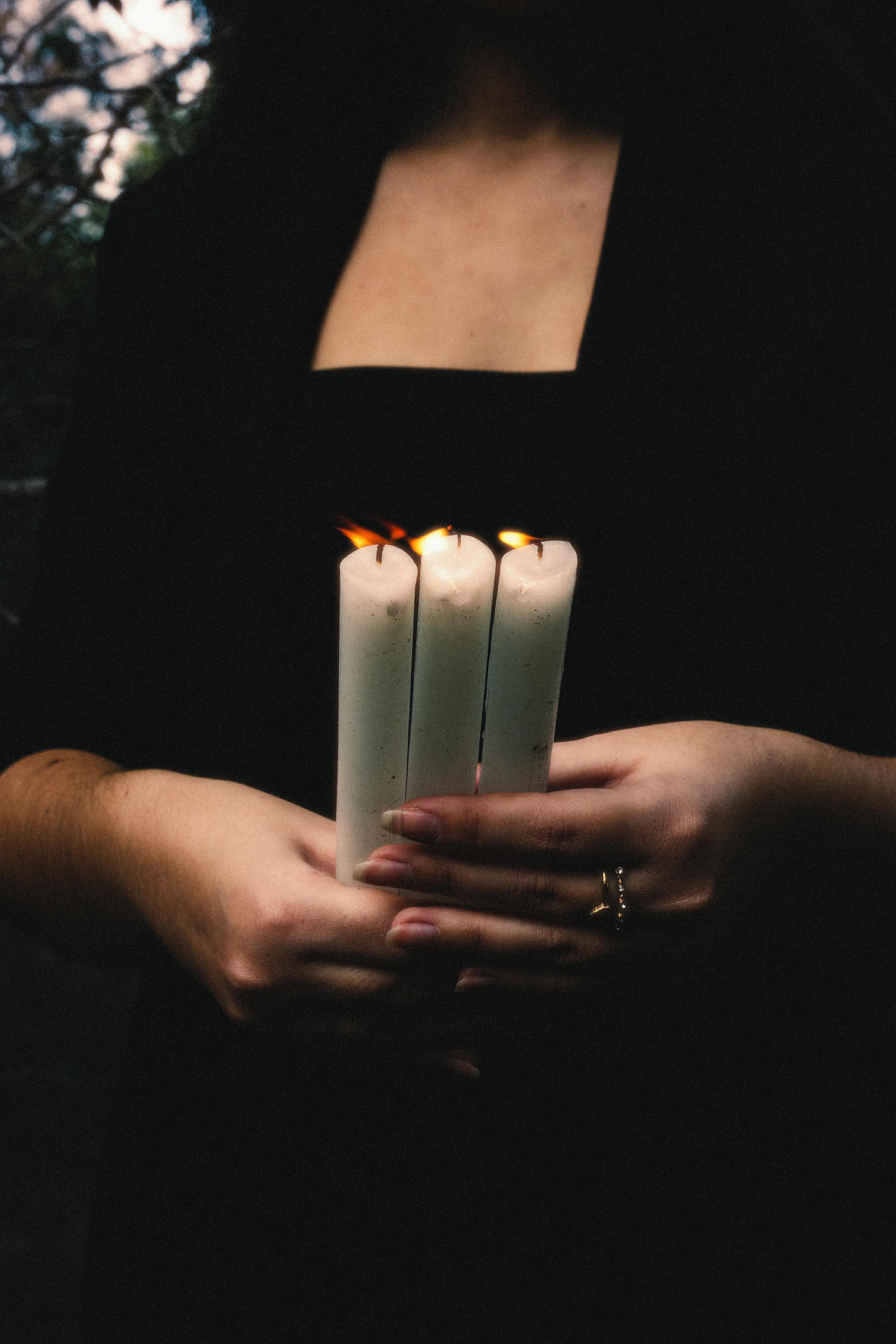 a woman holding a lit candle in her hands, inspired by Elsa Bleda, pexels, funeral, paul barson, white candles, multiple