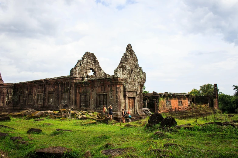 a group of people standing in front of a building, a picture, angkor thon, background image, valle dei templi, distant photo