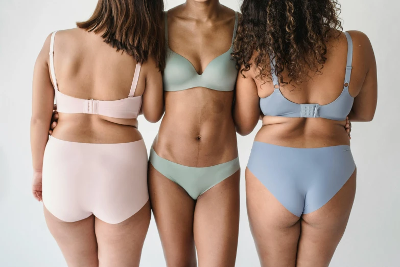 three women in underwear standing next to each other, trending on pexels, light blue skin, muted colours, different shapes and sizes, multi - coloured