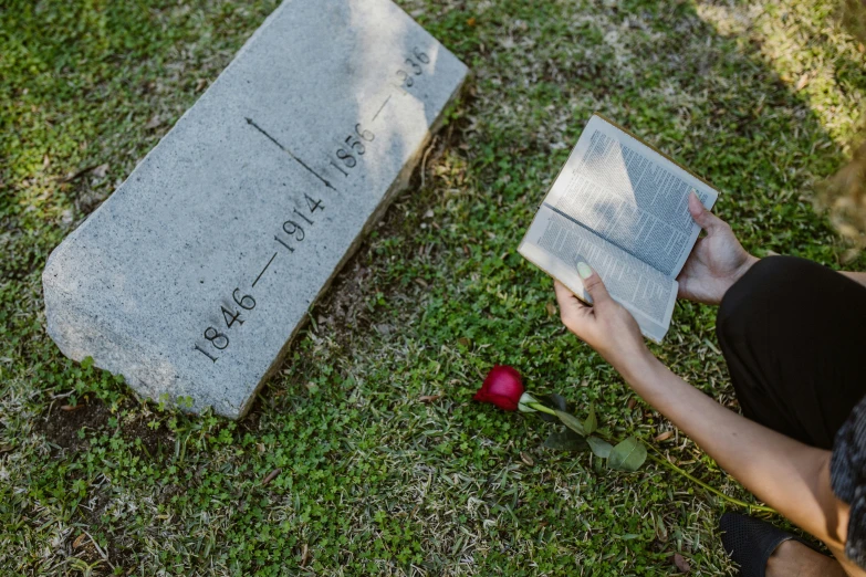 a person sitting on the ground reading a book, unsplash, magic realism, grave, holding a rose, 15081959 21121991 01012000 4k, tombstone