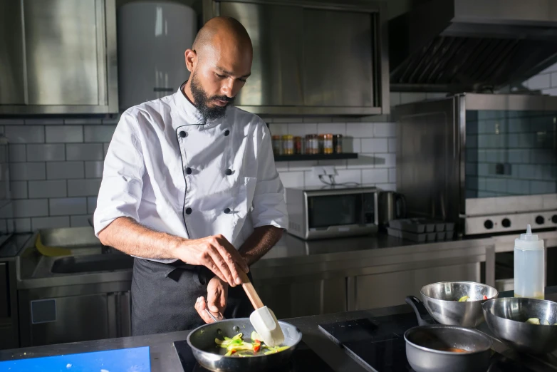 a man in a kitchen preparing food on a stove, inspired by Barthélemy Menn, pexels contest winner, navid negahban, profile image, three michelin star, ethiopian