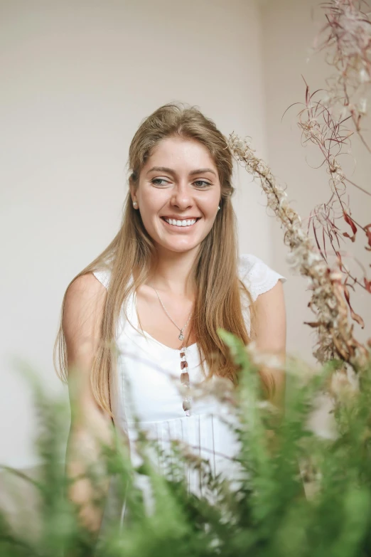 a woman standing in front of a bunch of plants, beautiful and smiling, dried flowers, profile image, naturalist