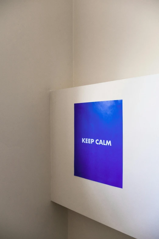 a white wall with a blue sign that says keep calm, a poster, inspired by Yves Klein, unsplash, temporary art, holographic projection, on vellum, medium close shot, looking off to the side