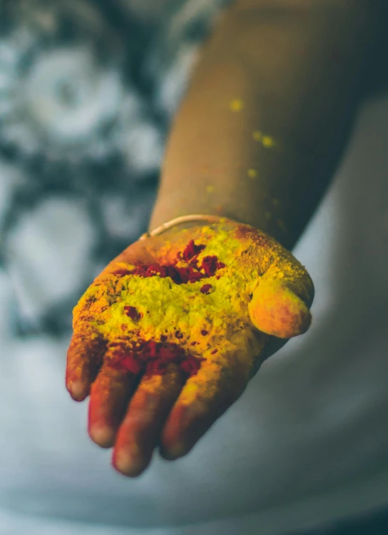 a person holding a piece of food in their hands, a colorized photo, inspired by Steve McCurry, trending on unsplash, holi festival of rich color, yellow and red, “ painting, indian