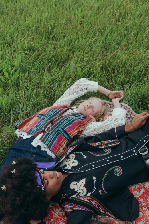 a couple of women laying on top of a lush green field, an album cover, by Alice Mason, trending on pexels, renaissance, embroidered shirt, ukrainian national clothes, in style of alasdair mclellan, gucci clothes