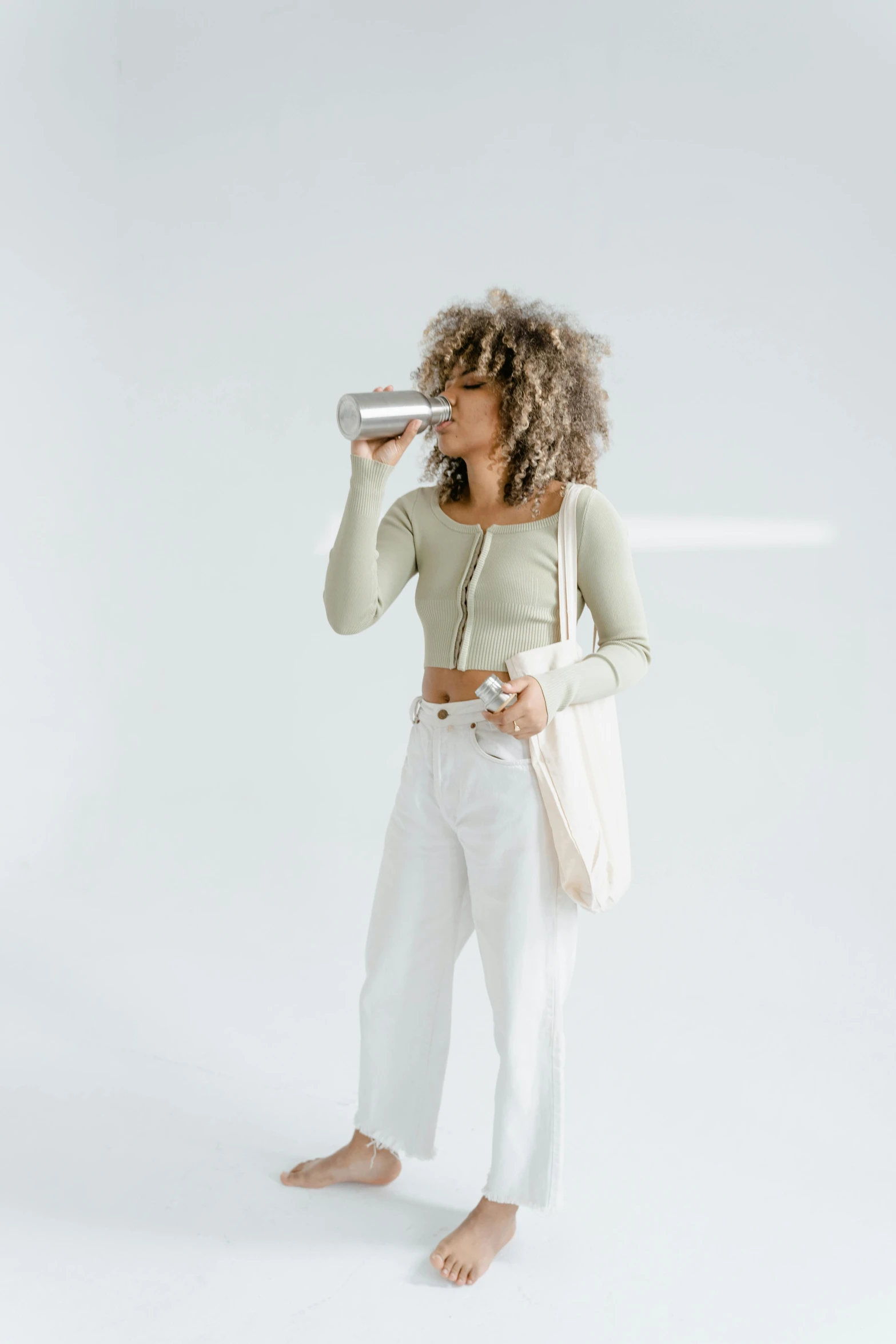 a woman taking a picture of herself in a studio, a digital rendering, trending on pexels, renaissance, peacefully drinking river water, white pants, curly haired, modern fashion outfit