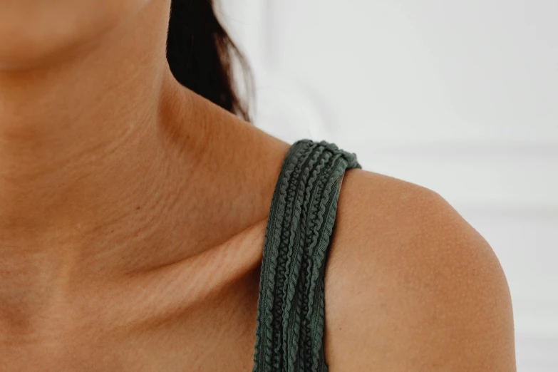 a close up of a woman wearing a green top, by Emma Andijewska, hurufiyya, straps, natural skin, crochet skin, detailed product shot