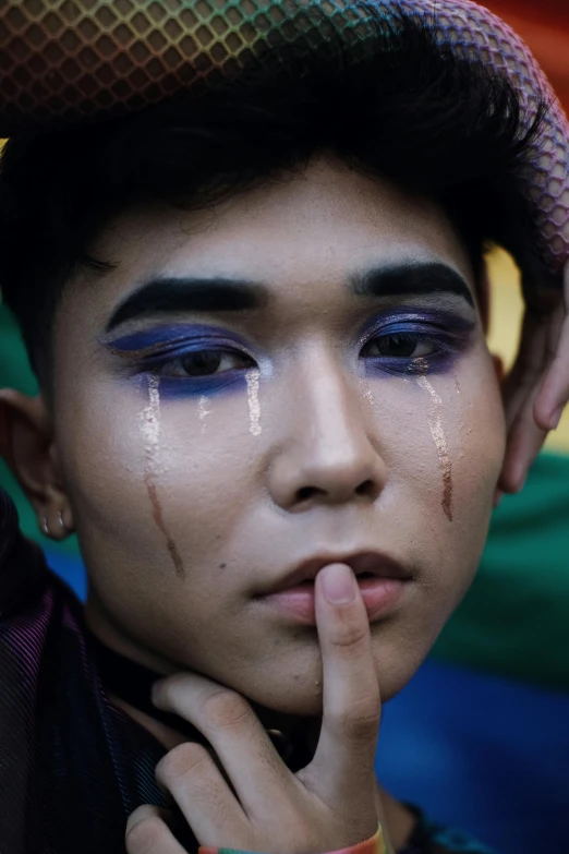 a close up of a person with a hat on, an album cover, by Basuki Abdullah, trending on pexels, crying makeup, gay pride, boy, mime