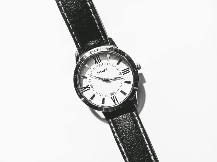 a close up of a wrist watch on a white surface, a stipple, pexels, fluxus, times magazine, black leather accents, roman numerals, trimmed with a white stripe