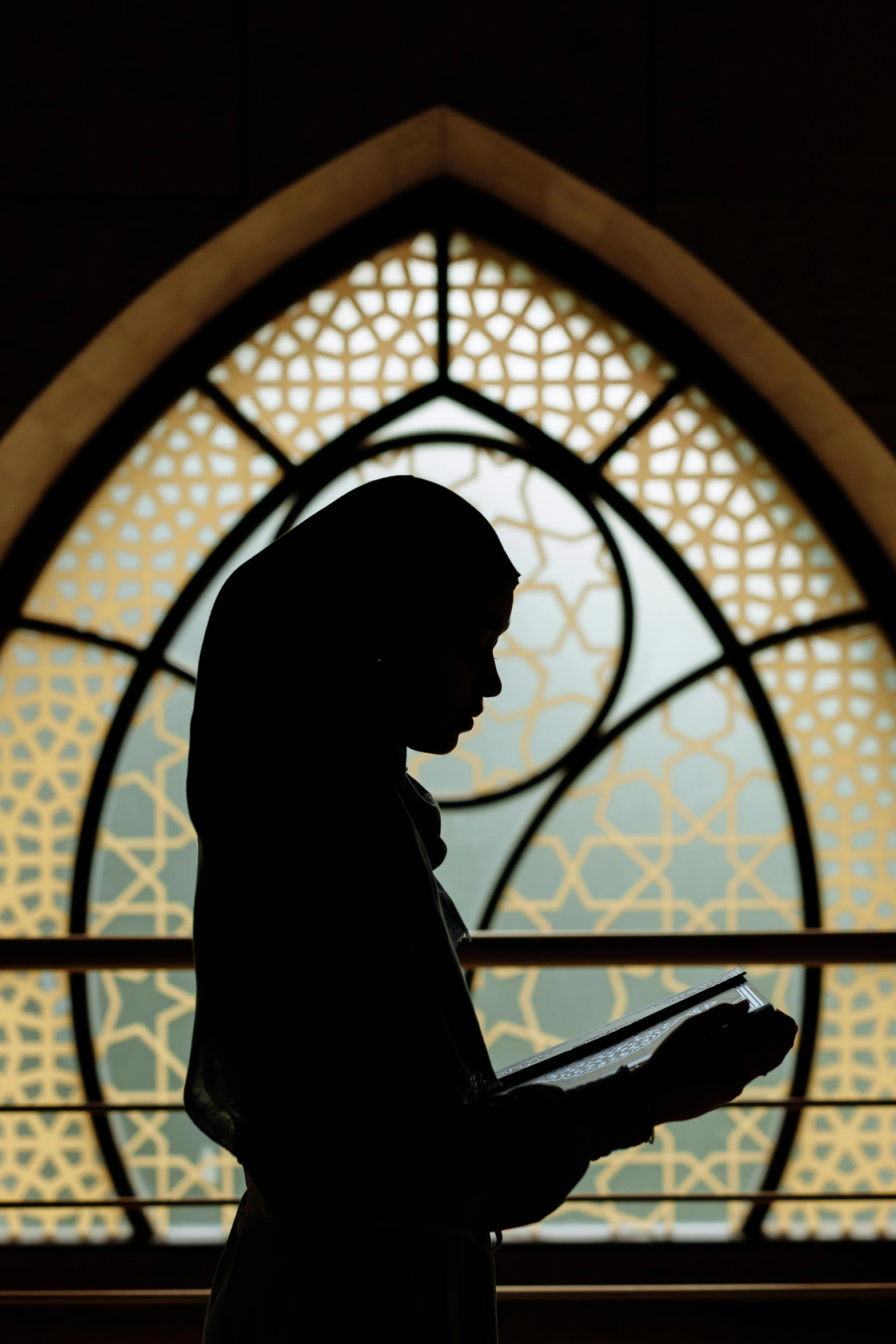 a person standing in front of a stained glass window, hurufiyya, reading, woman silhouette, photograph credit: ap, multiple stories