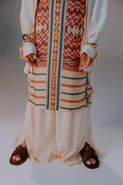 a man standing with his hands in his pockets, an album cover, inspired by Modest Urgell, hurufiyya, detailed clay model, embroidered robes, full body! shot, multicoloured