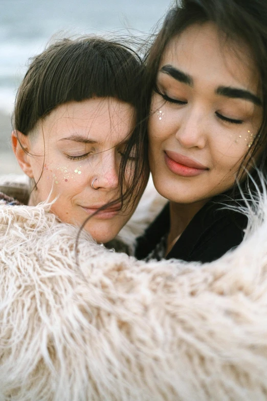 two women hugging each other on the beach, trending on pexels, renaissance, covered in soft fur, sparkles on eyelids, androgynous person, brunette