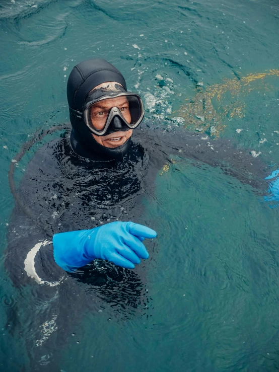 a man in a wet suit and goggles in the water, balaclava, nanae kawahara, wearing gloves, clear blue water