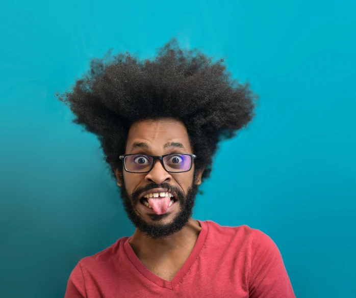 a man with an afro sticking out his tongue, pexels contest winner, with a blue background, nerdy appearance, goatee, flipped out hair