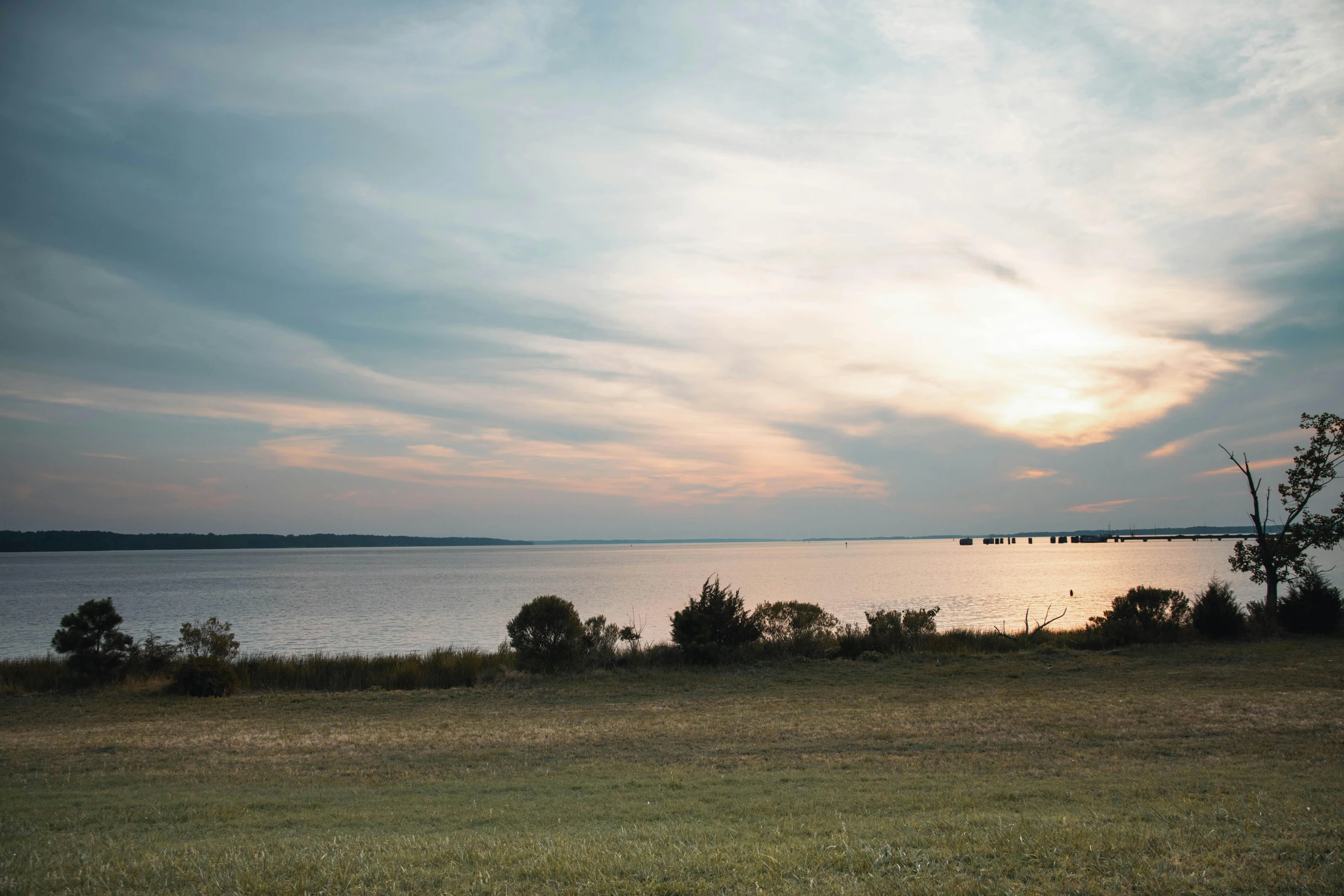 a red fire hydrant sitting on top of a lush green field, by Carey Morris, pexels contest winner, happening, which shows a beach at sunset, wide river and lake, washington dc, panorama distant view