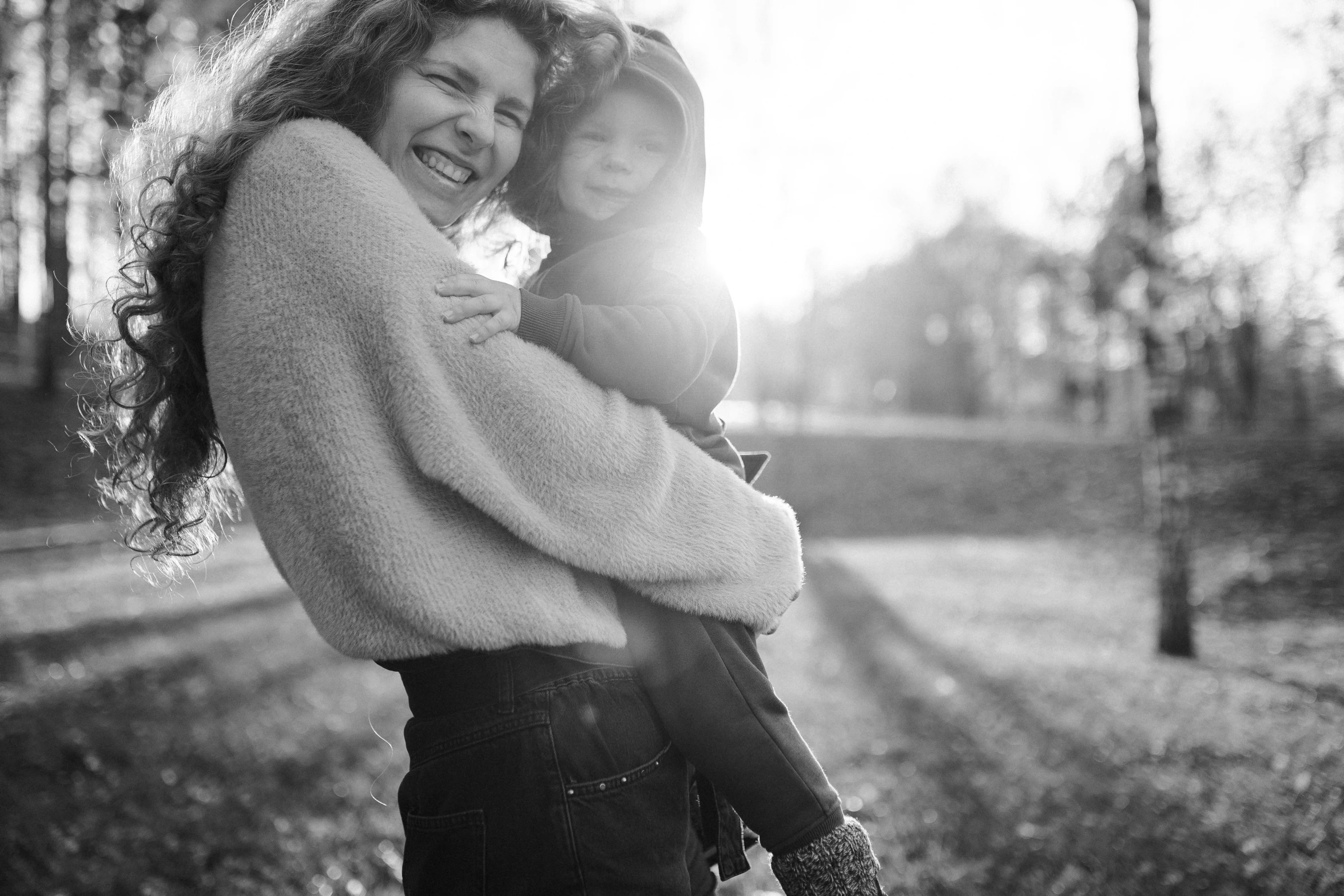 a woman holding a little girl in her arms, a black and white photo, by Emma Andijewska, pexels, at the park on a beautiful day, warm smile, videogame still, infp young woman