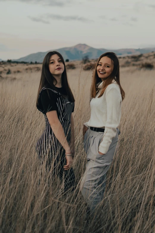 two women standing in a field of tall grass, a picture, trending on unsplash, teenage, plain background, avatar image, mountainside