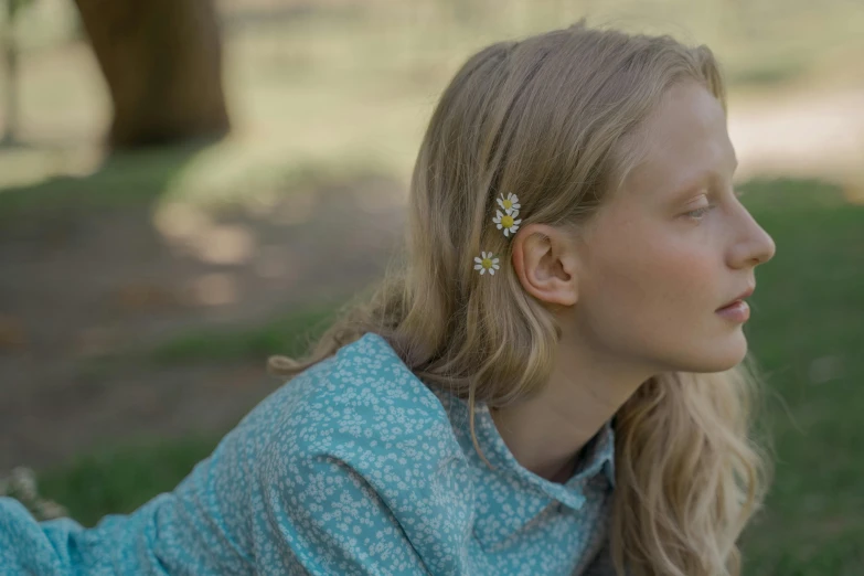 a woman laying on top of a lush green field, by Emma Andijewska, trending on pexels, hyperrealism, chamomile, earring, enamel, still from a live action movie