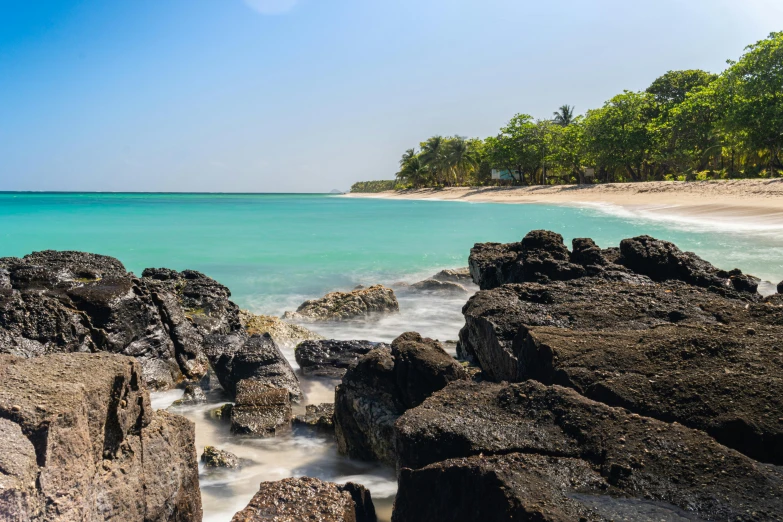 a beach filled with lots of rocks next to the ocean, tropical trees, avatar image, conde nast traveler photo