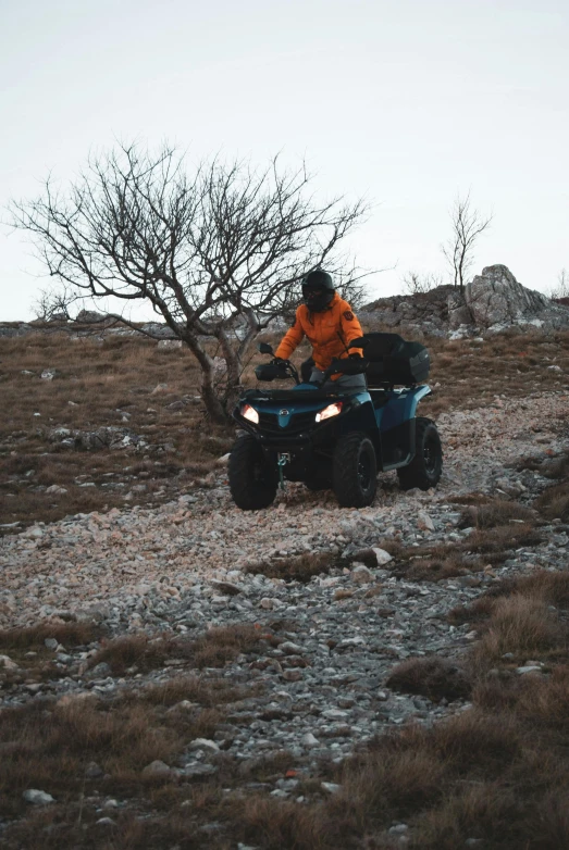 a man riding on the back of an atv, by Adam Szentpétery, pexels contest winner, square, dark grey and orange colours, nina tryggvadottir, hill