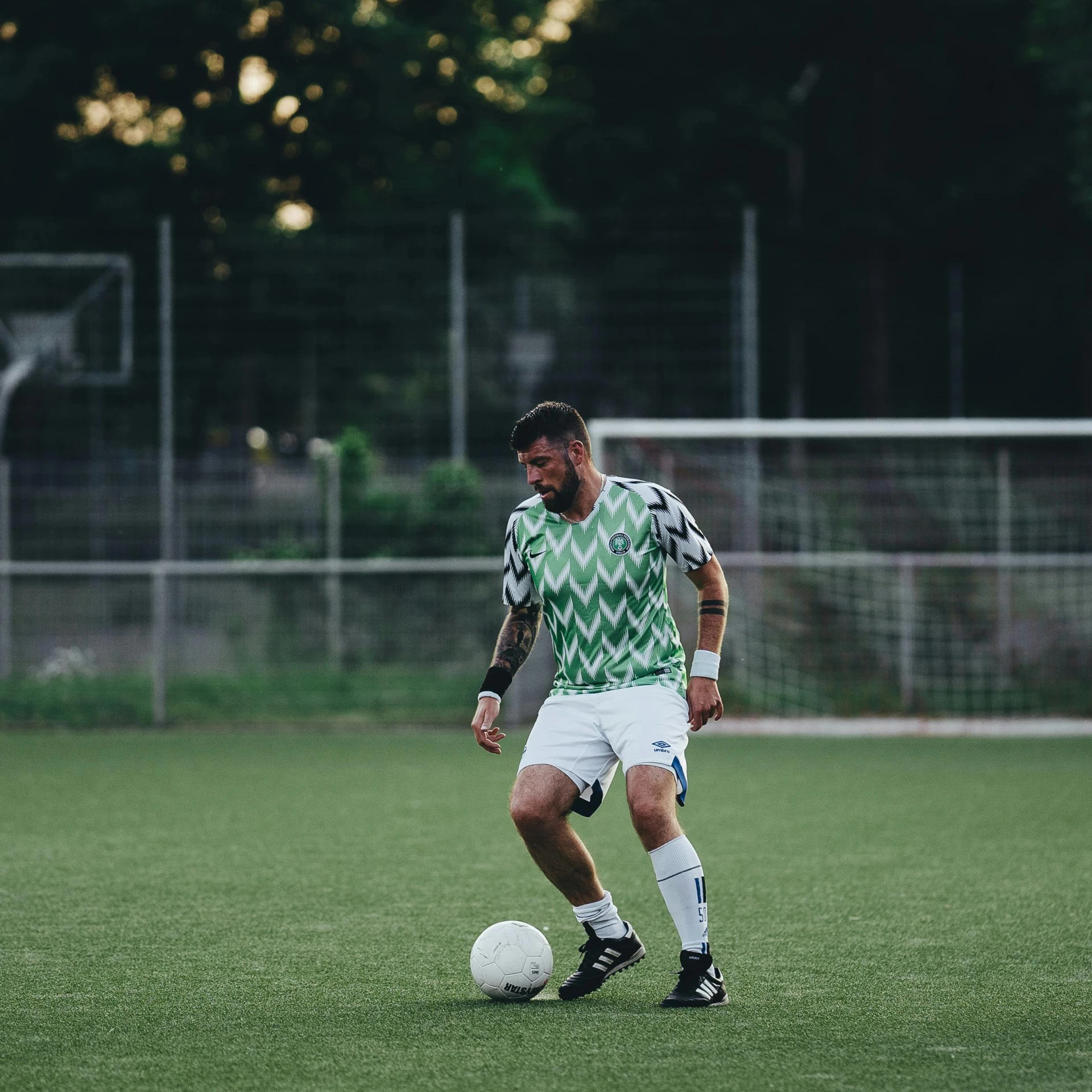 a man that is standing in the grass with a soccer ball, on the field