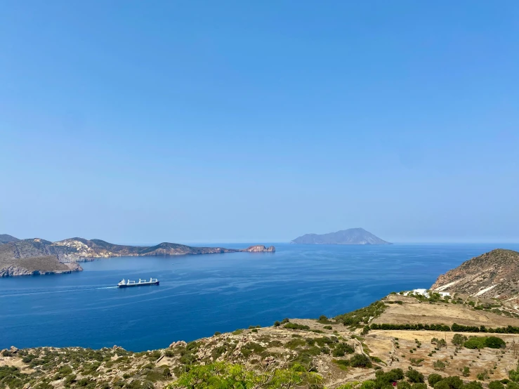 a large body of water sitting next to a lush green hillside, by Exekias, island in a blue sea, exclusive, thumbnail, greek ameera al taweel