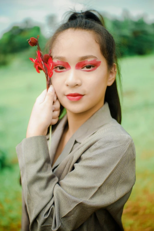 a woman standing in a field with a flower in her hand, an album cover, inspired by Natasha Tan, wearing professional makeup, red palette, asian, portrait n - 9