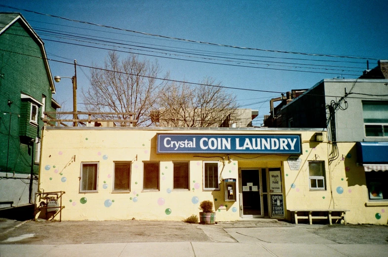 a yellow building with a sign that says crystal coin laundry, a colorized photo, instagram, alessio albi, lined in cotton, coins, 1990's photo