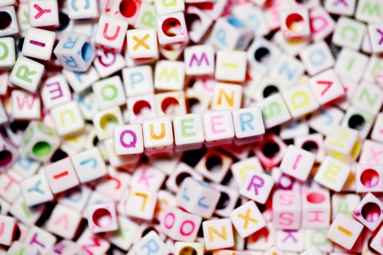 a pile of letters sitting on top of a table, by Joe Bowler, pexels, letterism, ru paul\'s drag race, square, queen, beads